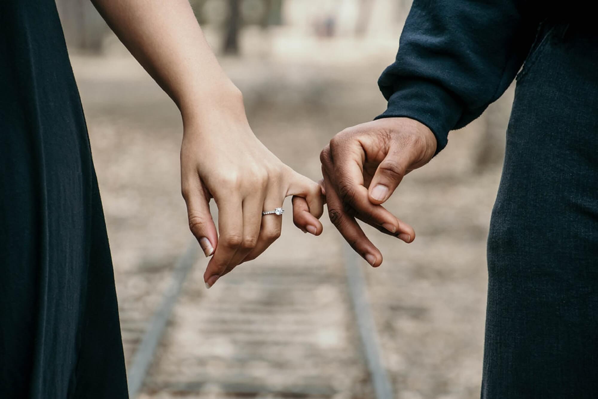 imagem das mãos de casal inter-racial representando sonhar com casamento