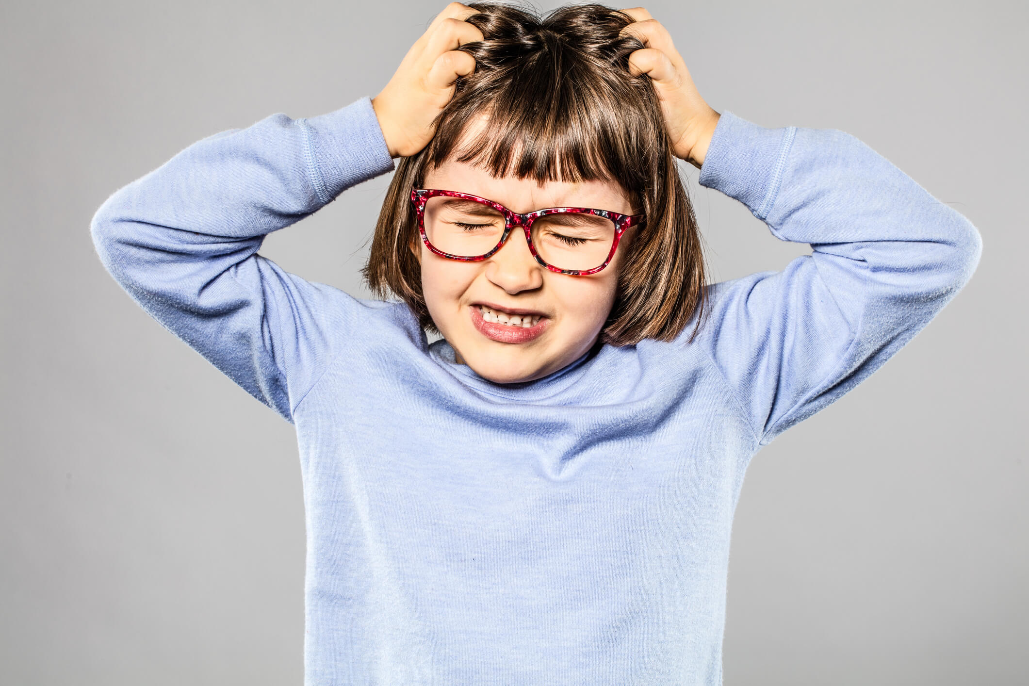 foto de criança usando óculos coçando a cabeça representando sonhar com piolho