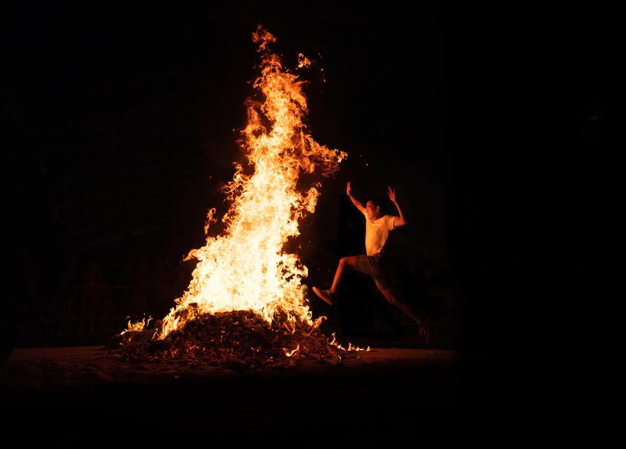 fotografia de pessoa pulando ao lado de fogueira para representar sonhar com fogo