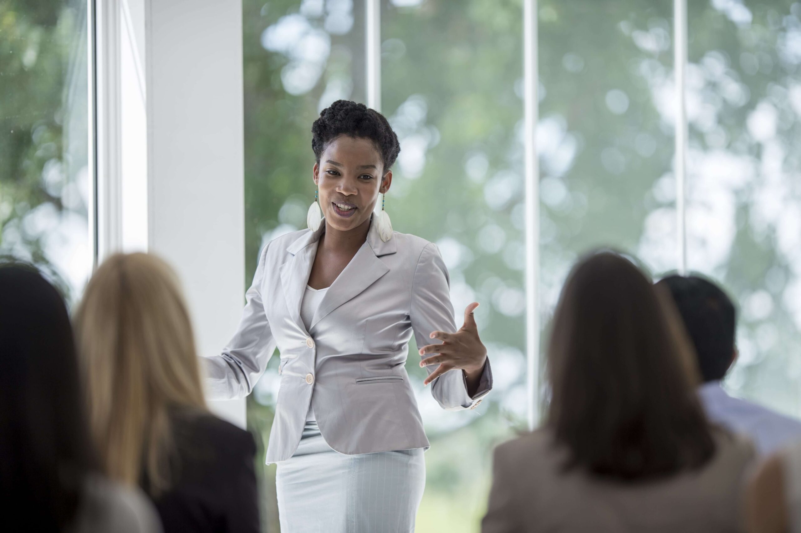 Mulher vestindo roupa social, com blazer e saia, em uma reunião representando a liderança situacional