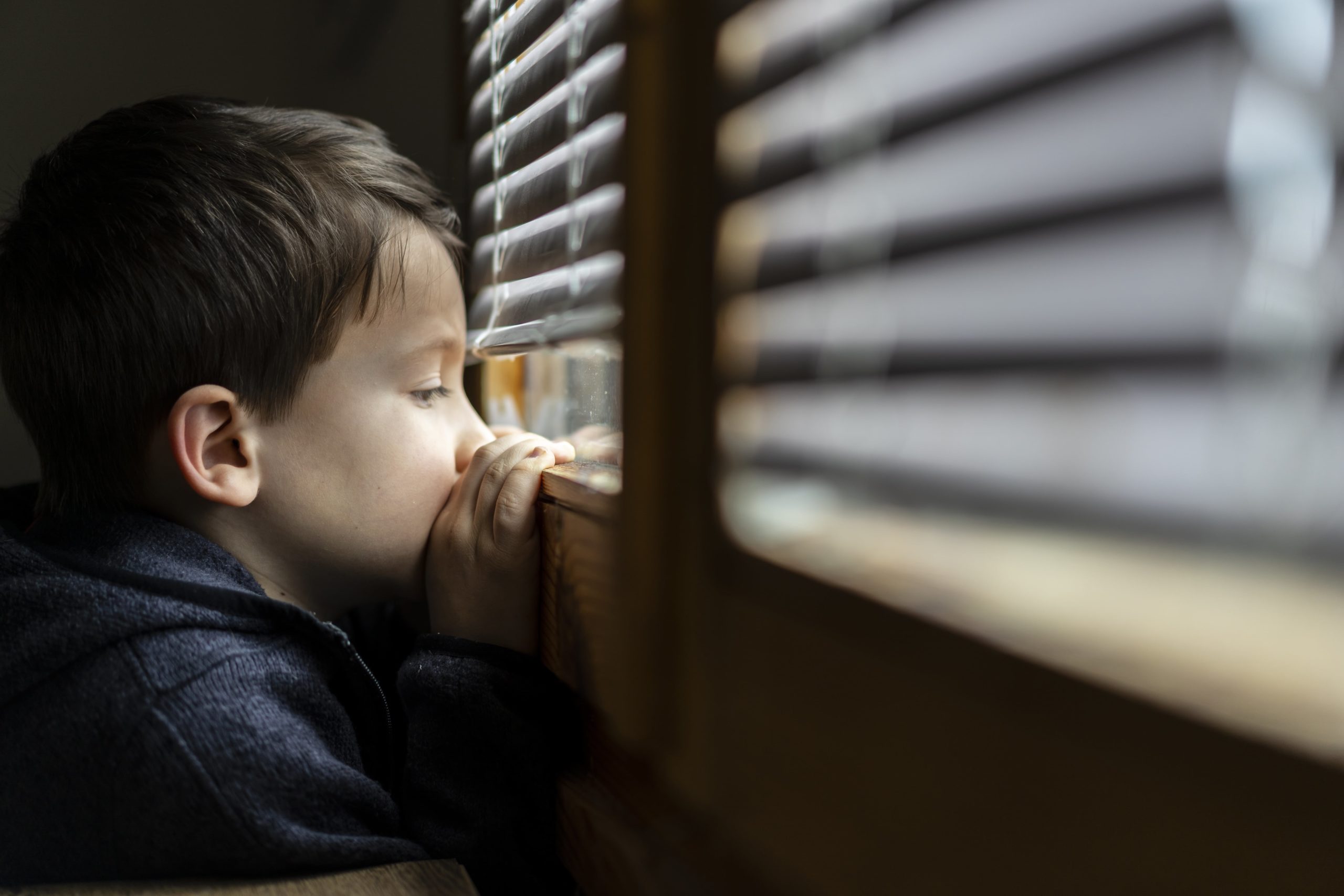 menino olhando depressivo para a janela